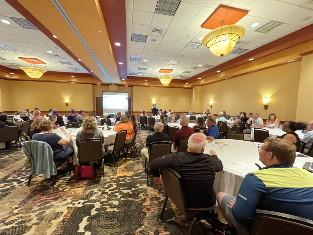 Conference attendees sitting at table watching presentation