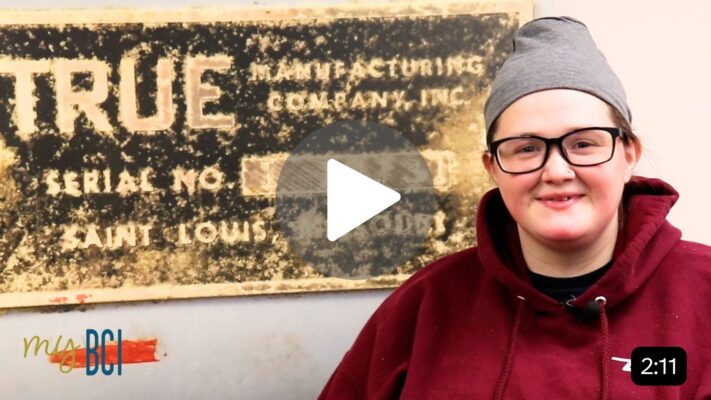 Photo of young woman smiling in front of True Manufacturing sign